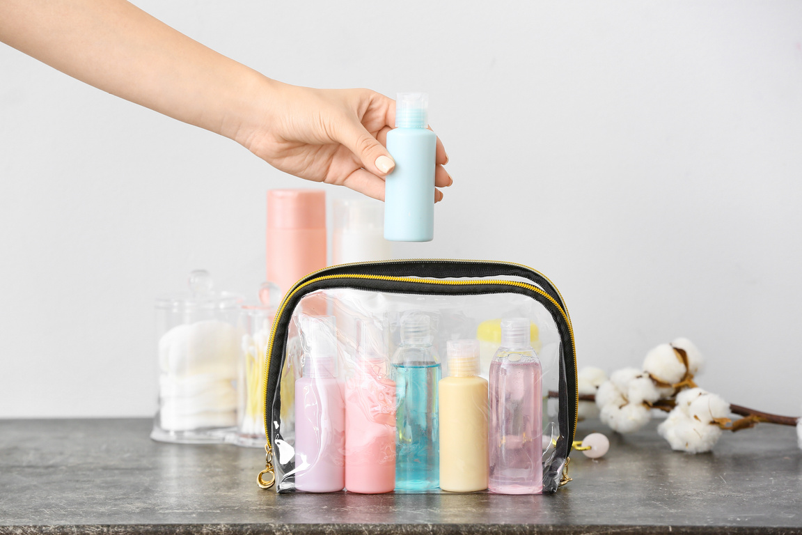 Female Hand and Travel Cosmetics Kit on Table